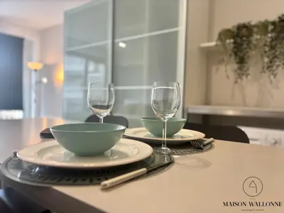 a table with two plates and two wine glasses at Le studio de la Cathédrale - Hypercentre avec balcon in Liège