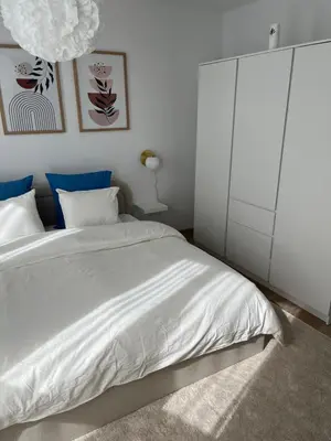 a bedroom with a white bed and a white cabinet at Appart lumineux avec terrasse au cœur de Liège in Liège