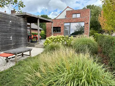a garden with a bench in front of a house at Vakantiewoning De Vliergeit in Limburg - Haspengouw in Hasselt