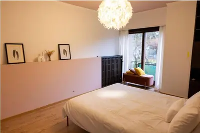 a bedroom with a bed and a chandelier at Maison modernisée au caractère 70ies in Herstal