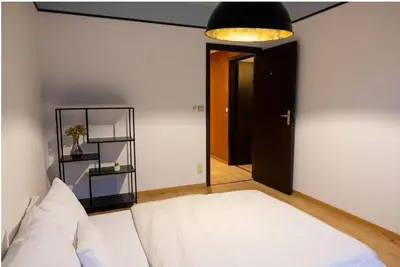 a bedroom with a white bed and a black door at Maison modernisée au caractère 70ies in Herstal