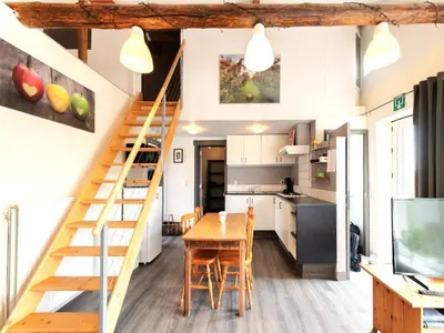 a kitchen and dining room with a wooden table and stairs at Farmhouse with garden and wellness in Heers