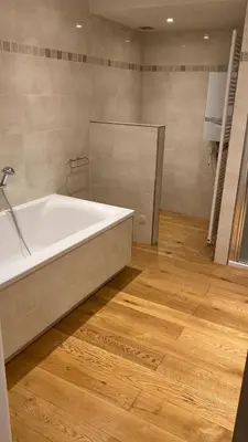 a bathroom with a tub and a wooden floor at Residentie Ons Genoegen in Lommel