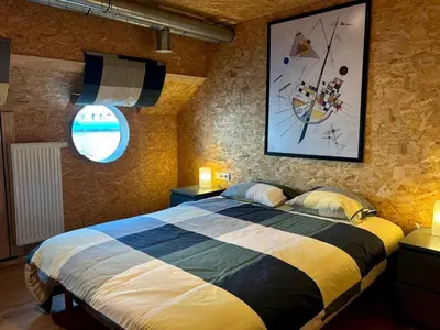 a bedroom with a large bed with a picture on the wall at La péniche de Santa Cruz - Sur la Meuse, centre ville in Liège