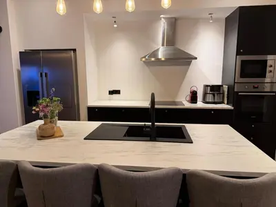 a kitchen with a sink and a counter with chairs at Premium apartment at the gates of Liège in Liège
