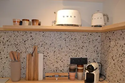 a kitchen counter with wooden shelves with appliances at Maison au coeur du village in Aubel