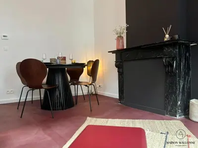 a living room with a table and chairs and a fireplace at Le Red Velvet - Hypercentre, pour 2 personnes in Liège