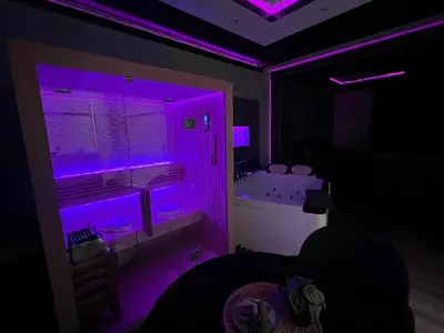 a room with a purple lighted bathroom with a tub at Pause Thermale Suite in Herstal