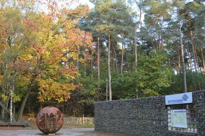a sign in front of a stone wall next to a fence at Twinstone Lodge in Genk