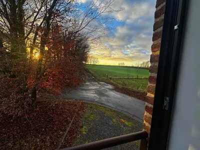 a view from a window of a road with the sunset at Le Chen Zen in Dalhem