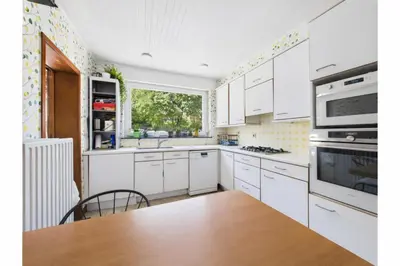 a kitchen with white cabinets and a table and a window at Maison de Maître in Liège