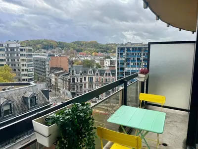 a balcony with a table and chairs and a city at Avenue Rogier in Liège