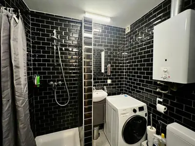 a black tiled bathroom with a sink and a shower at Le studio de la Boverie - Entièrement équipé in Liège