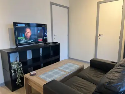a living room with a couch and a flat screen tv at Le studio de la Boverie - Entièrement équipé in Liège