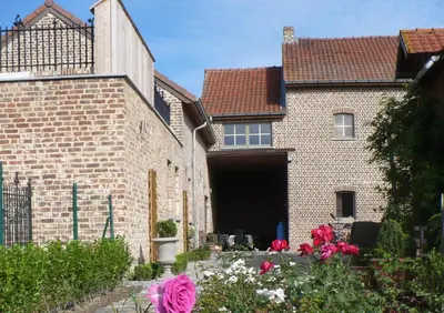 a brick house with a garage and some flowers at B&B Kamer en Aambeeld in Zoutleeuw