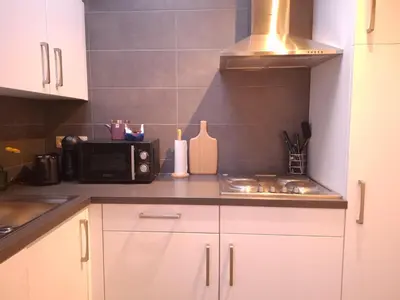 a kitchen with white cabinets and a microwave at Cocon Liégeois in Liège