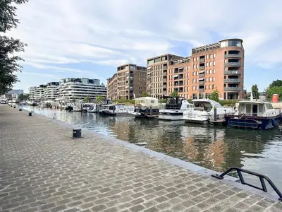 a group of boats docked in a river with buildings at Holiday home in the heart of Hasselt in Hasselt