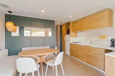 a kitchen with a wooden table and white chairs at Camping Papillon Kinrooi - Vakantiehuis Premium 4P in Kinrooi