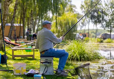 a man sitting on a block holding a fishing pole at Camping Papillon Kinrooi - Vakantiehuis Premium 4P in Kinrooi