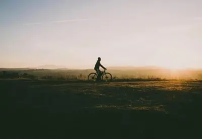 a person riding a bike on a field at sunset at Camping Papillon Kinrooi - Pipowagen 2p terras in Kinrooi