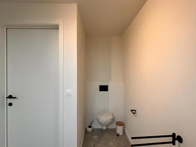a bathroom with a white toilet and a door at Spacious 3-Floor Holiday Home for 8 Guests in Bree