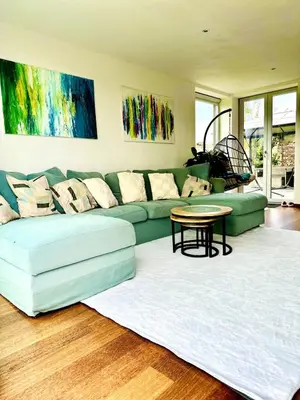a living room with a green couch and a table at Dukes View -explore Haspengouw & surrounding towns in Zoutleeuw