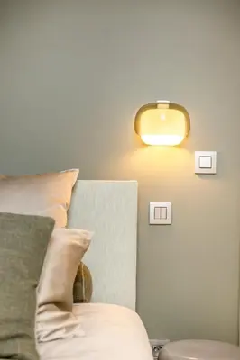 a light on a wall next to a bed with pillows at De Kompanie in Alken