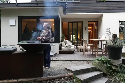 a woman standing outside of a house with a tv at Homestorys Nature Resort - Wood Lounge in Eupen