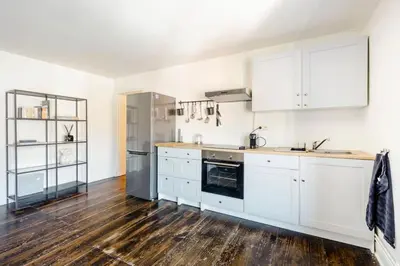a kitchen with white cabinets and a wooden floor at L'appartement Casquette in Liège