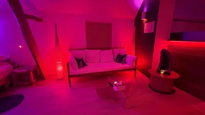 a living room with a couch in a pink room at L'Améthyste in Crisnée
