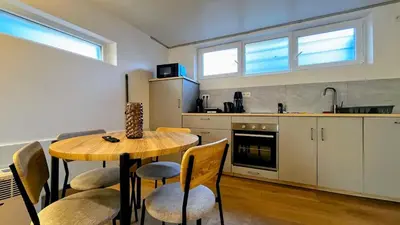a kitchen with a wooden table and chairs in a room at Chez Margueritte, Cosy, Jacuzzi & Parking Facile in Liège