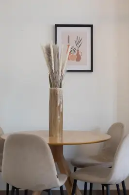 a dining room table with chairs and a vase with grass at Moni 2D Residence in Seraing