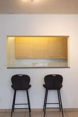 two black chairs sitting in front of a kitchen counter at Moni 2G Residence in Seraing