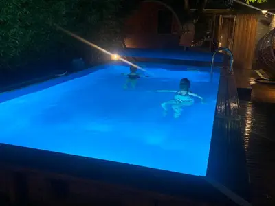 two people swimming in a pool with blue lights at Duplex 7 avec Spa Privé in Herstal