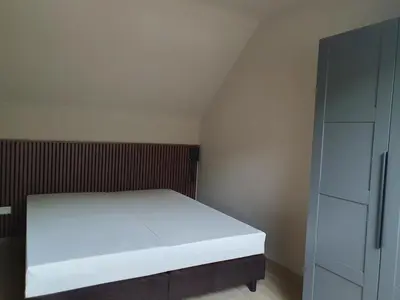 a bedroom with a white bed and a cabinet at Camping Natuurlijk Limburg - Appartement 6p in Voeren