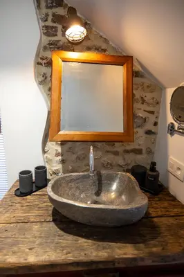 a bathroom with a stone sink on a wooden counter at les jardins de la ferme in Soumagne