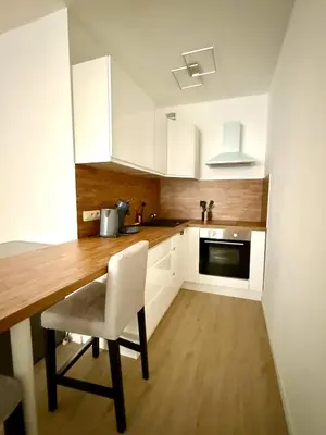 a kitchen with white cabinets and a table and a chair at Cosy studio en plein centre pour 2 personnes in Liège