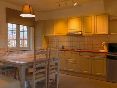 a kitchen with yellow cabinets and a wooden table and chairs at Holiday Home Heidebos für 8 Personen by Interhome in Oudsbergen