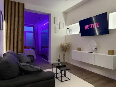 a living room with a couch and a tv on the wall at Suite Luxueuse avec jaccuzi sans vis-à-vis in Liège