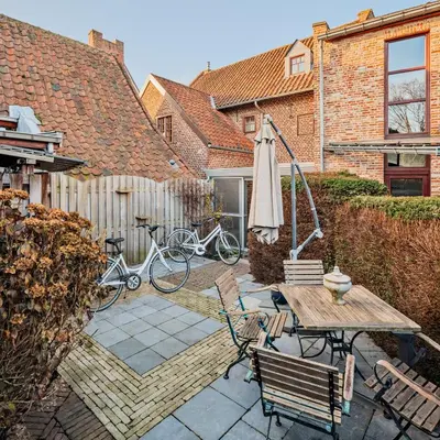 a patio with a table and an umbrella and a bike at Vakantiewoning Begijnhof 54 in Sint-Truiden