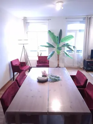 a living room with a wooden table and red chairs at L'Horizon Saint-Lambert in Liège