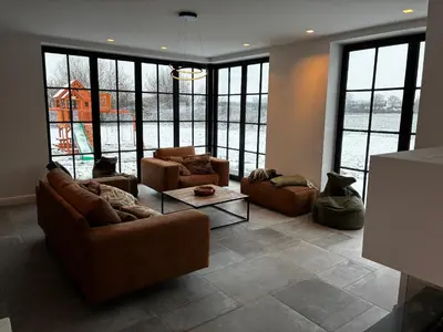 a living room with couches and tables and large windows at Hidden Secret of Nature in Neeroeteren