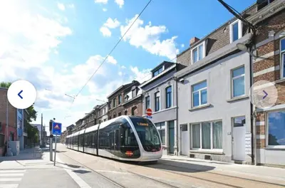 a train on a city street with buildings at Chic et cosy idéal pour un séjour à Liège in Liège