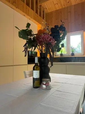 a bottle of wine and a vase with flowers on a table at Lysdann Zutendaal in Zutendaal