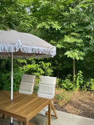a wooden table and two chairs under an umbrella at Lysdann Zutendaal in Zutendaal