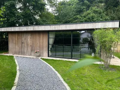 a building with glass windows in a garden at maison Clavita in Genk