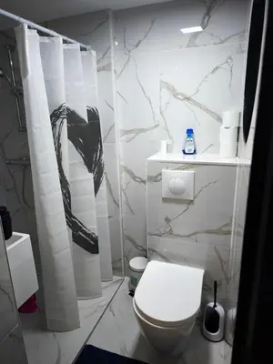 a bathroom with a white toilet and marble walls at Modern lux studio B in Beringen