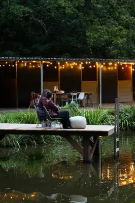 a man and woman sitting on a bench near a pond at Homestorys Nature Resort - Lakeview Pavilion in Eupen