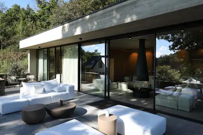 a living room with white furniture and glass walls at Homestorys Nature Resort - Lakeview Pavilion in Eupen