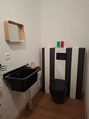 a bathroom with a black toilet and a sink at La Vie en Rose in Ensival